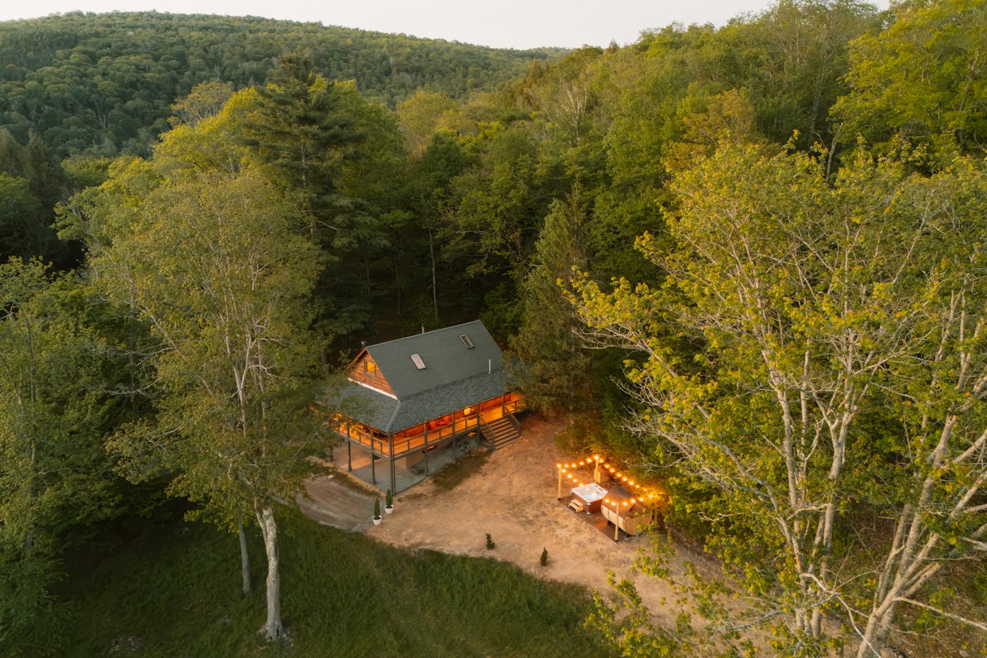 Forest cabin with a lit hot tub area at dusk